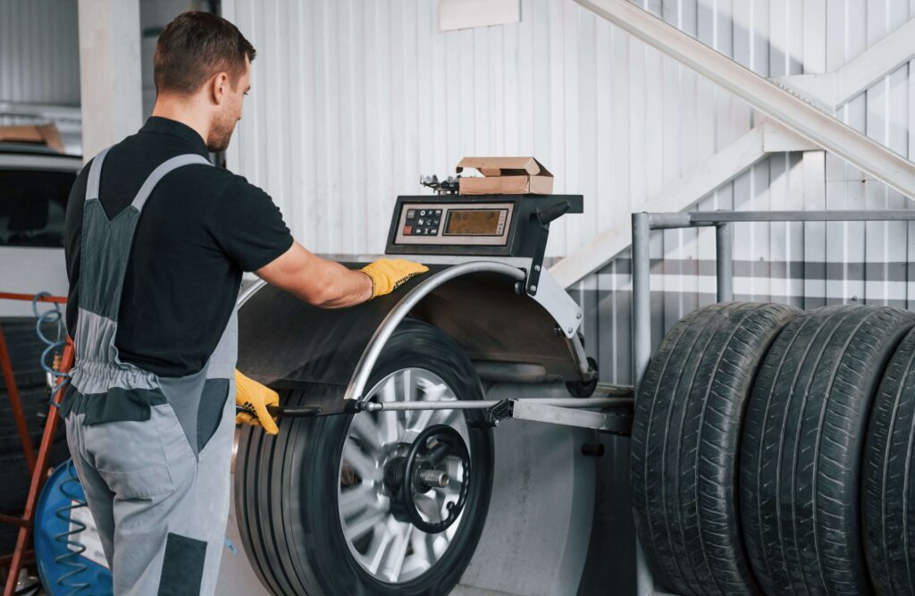 A technician performing tire balancing using a wheel balancer in an auto repair shop. The equipment ensures precise balance for smoother driving.