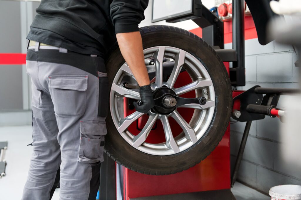 A mechanic mounting a car tire on a balancing machine to detect and correct weight imbalances for optimal tire performance.