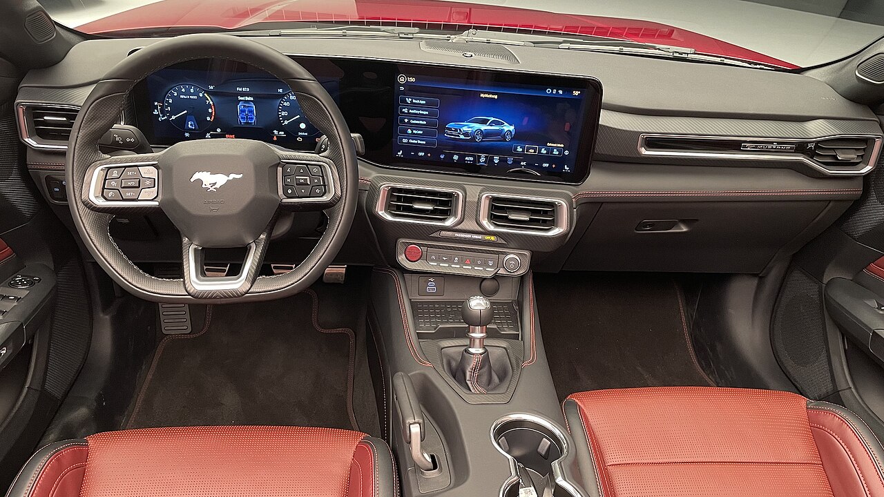 Interior of the 2024 Ford Mustang, highlighting a sleek, modern cabin with a fully digital driver display, a large touchscreen infotainment system, and high-quality materials on the seats and dashboard. The design combines sporty elements with advanced technology features.