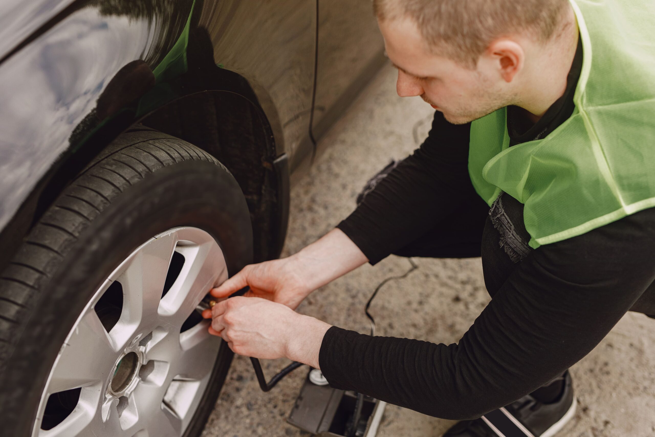 A man checking tire pressure, illustrating essential pre-trip vehicle maintenance for safe long-distance travel