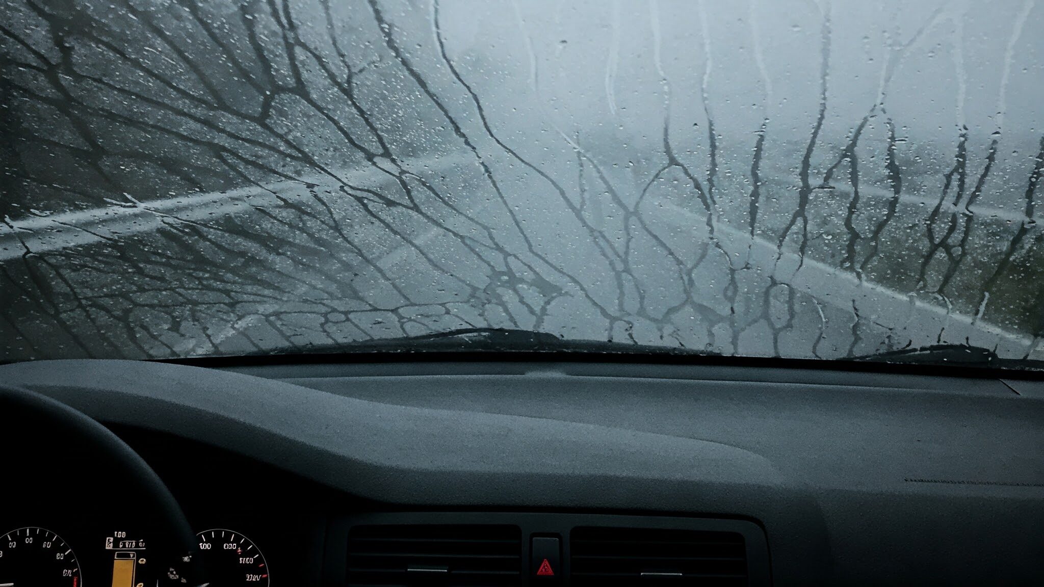 An inside view of a car with foggy windows. The car is on the road and on the move, but it seems that the windshield is foggy, thus limiting the vision of the driver. 