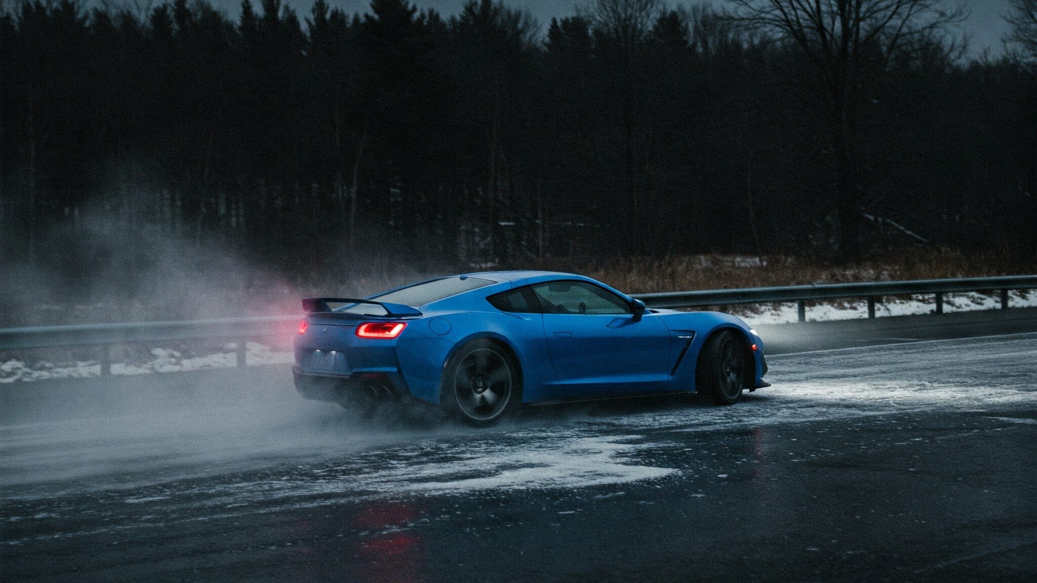 A blue sports car on a winter road covered with ice, trying to accelerate, but due to the ice buildup, its rear tires are sliding up.